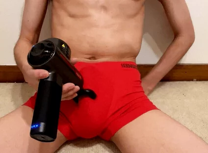 A Young Japanese Man Masturbates with a Massager Over His Red Boxer Shorts. He Has a Large Penis and Testicles.